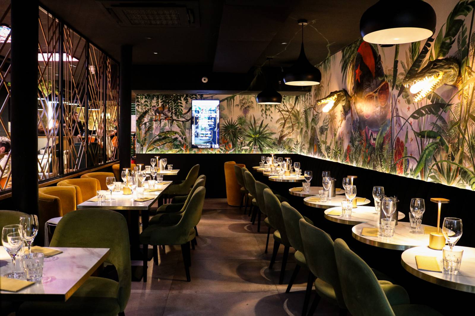Salle à manger, fauteuils velours vert et moutarde, fresque tropicale et singe.