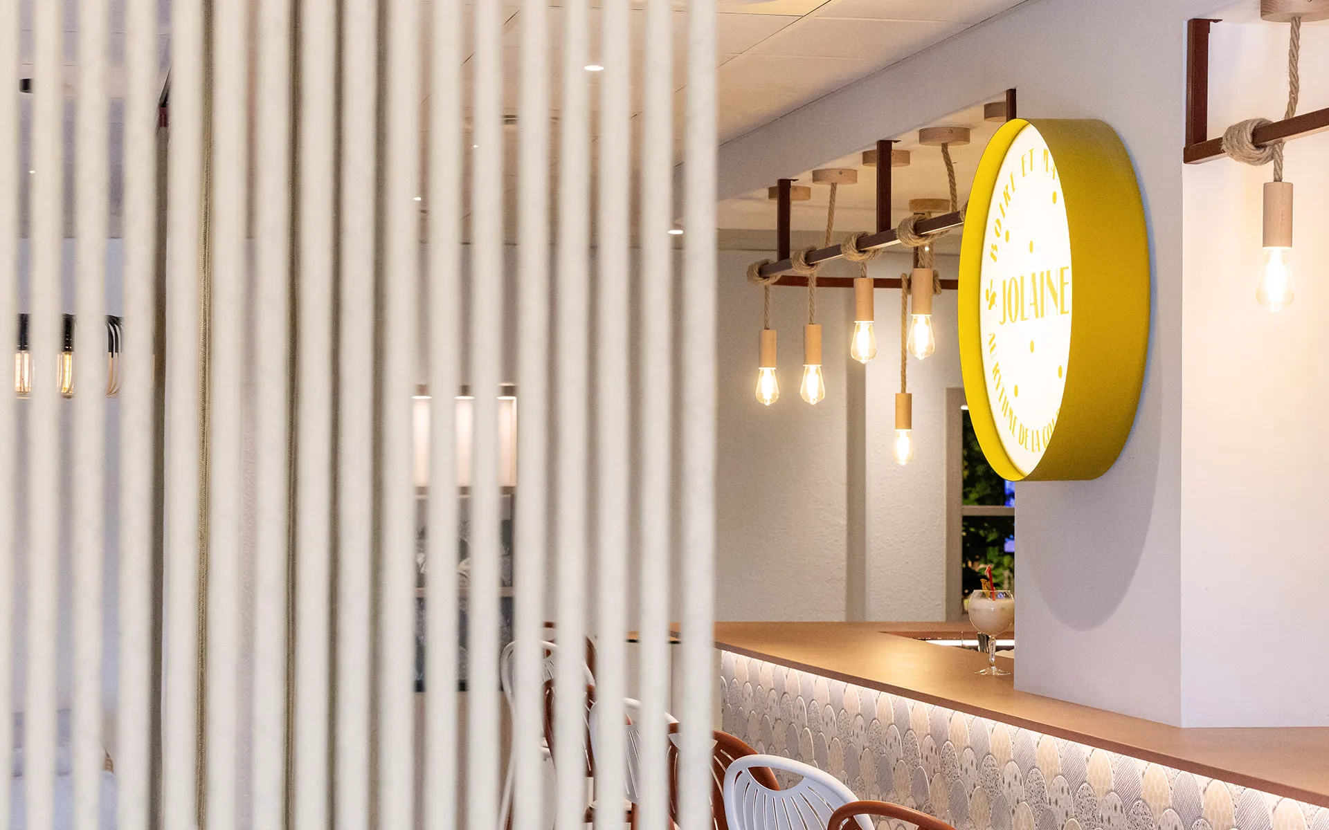 Enseigne ronde Jolaine et suspensions en bois au-dessus du bar