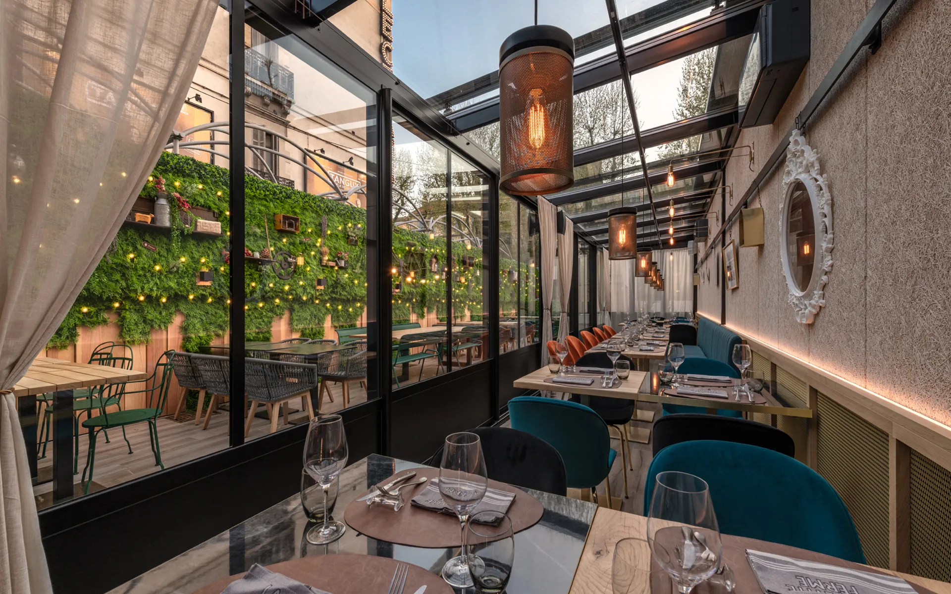 Salle en verrière, banquette bleu pétrole et suspensions cuivrées.