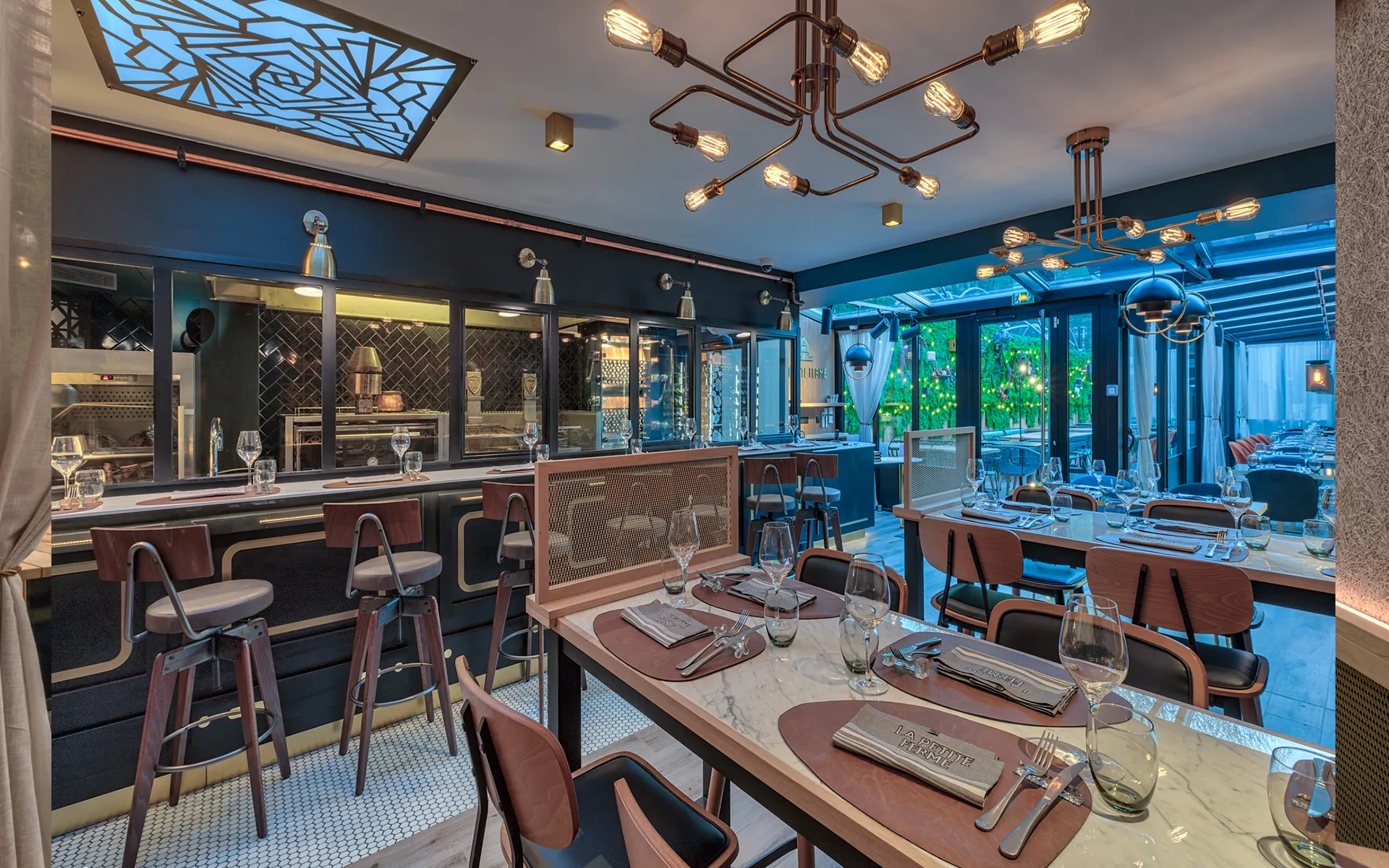Comptoir en marbre, tabourets en cuir et cuisine ouverte en fond.