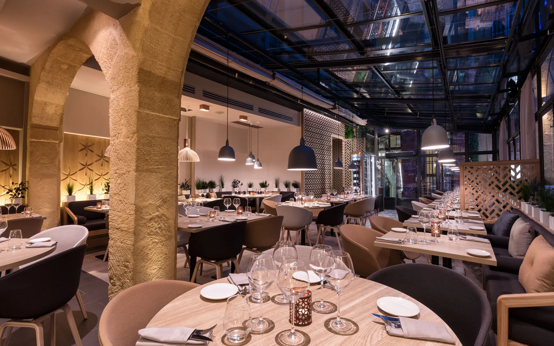 Salle à manger de nuit, tables dressées, verrière et rideaux