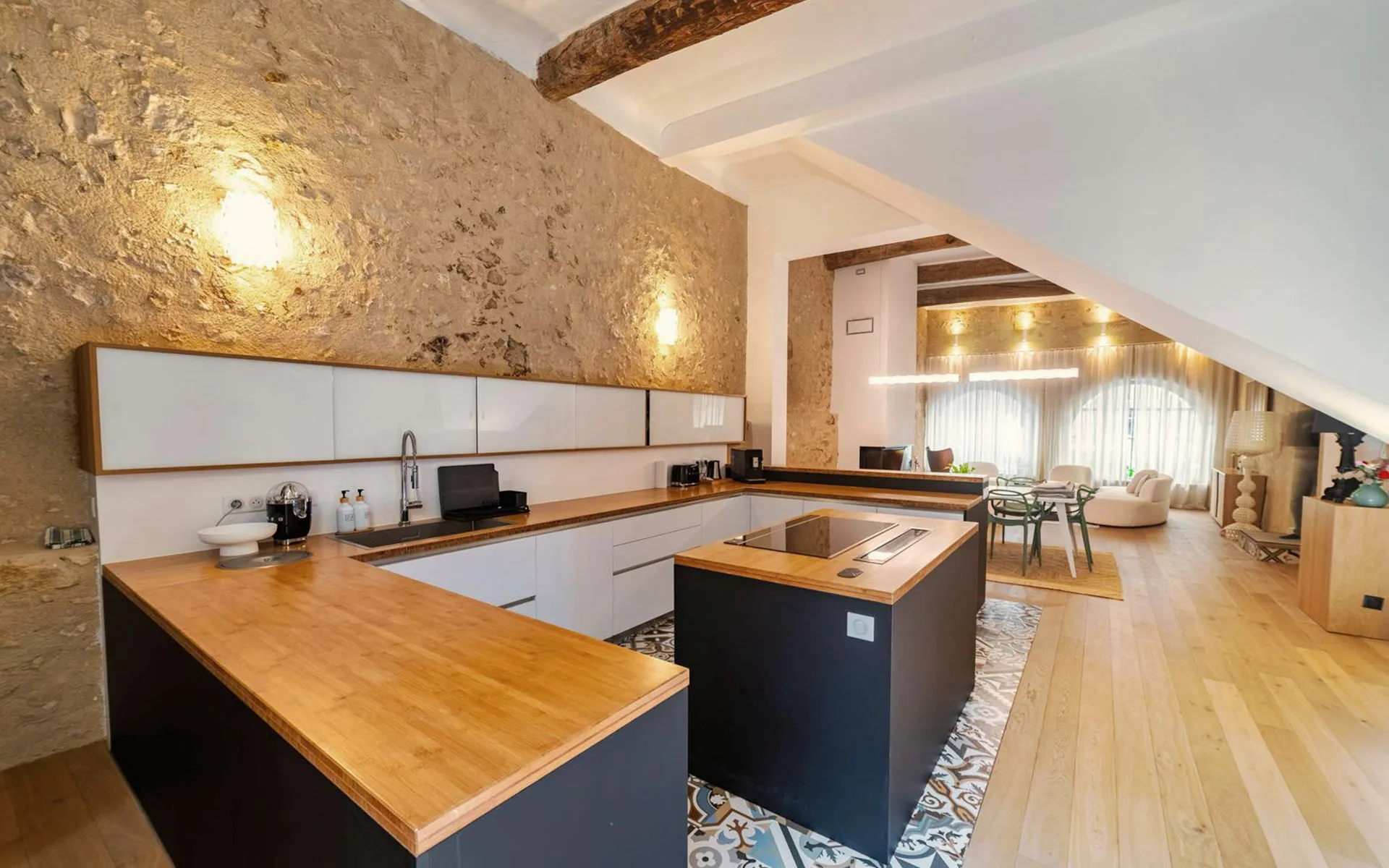 Cuisine ouverte en U, plan de travail bois et façades foncées.